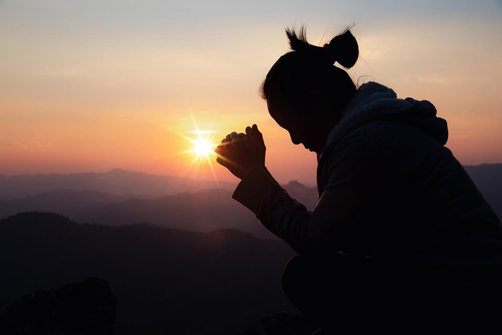 Mulher de luto orando em frente ao por do sol