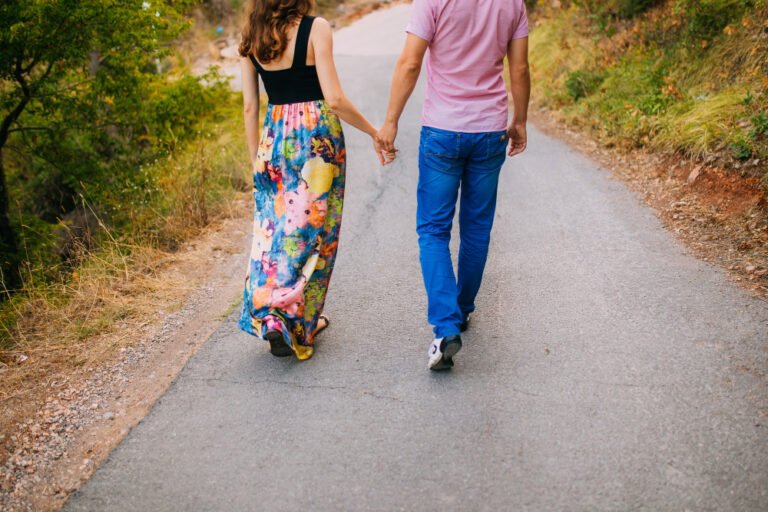 Casal de homem e mulher caminhando junto por um caminho envolto pela natureza