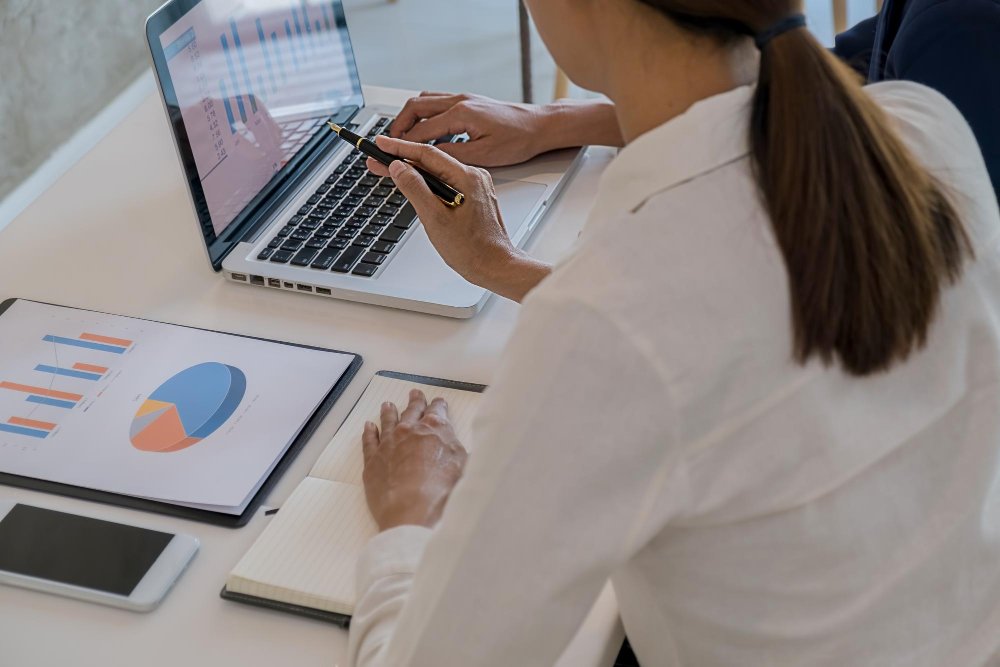 Profissionais analisando gráficos em laptop, representando como o Copilot da Microsoft aumenta a produtividade e a colaboração nas empresas